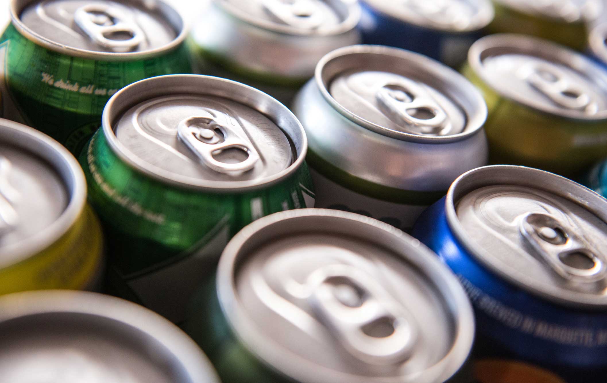 Closeup of canned drinks lined up at the bar — aluminum tops and brand colors.